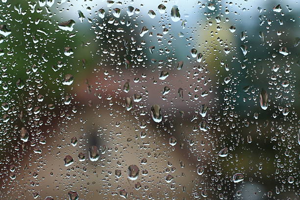 istock Rain drops on window with house and church in background 577323418