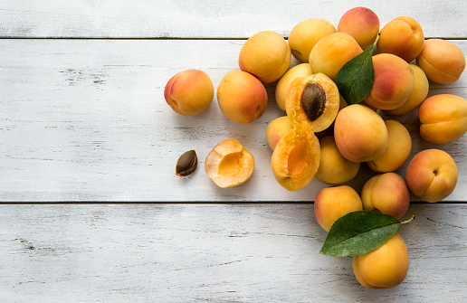 Fresh apricots on white wooden table.
