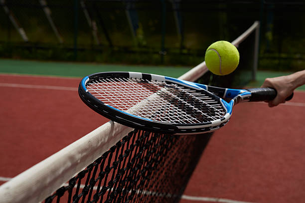 istock tennis racquet, ball and net 577330698