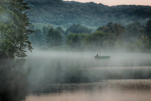 Lonely boat on a slow river in the morning mist