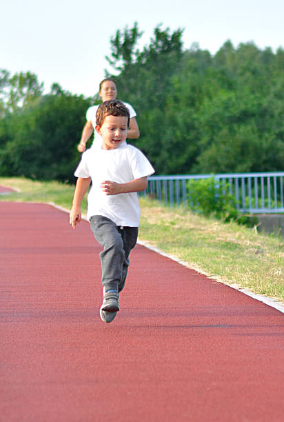 Family recreation. A child and his mom running on jogging track.