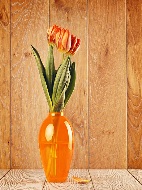 A serene scene of lighting and smelling joss sticks, with a soft focus on a floral arrangement in the background
