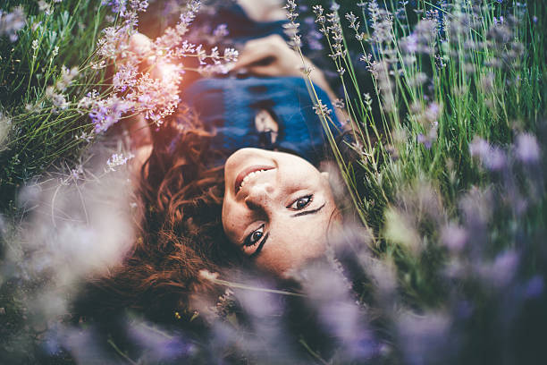 beautiful woman freckles laying in lavander field, looking at camera.