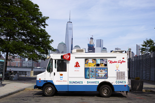 Jersey City, USA - July 4, 2016: White Mister Softee ice cream truck in Jersey City with New York financial district WTC skyscraper in background
