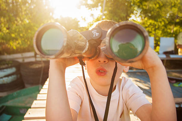Little boy looking through binoculars on river bank