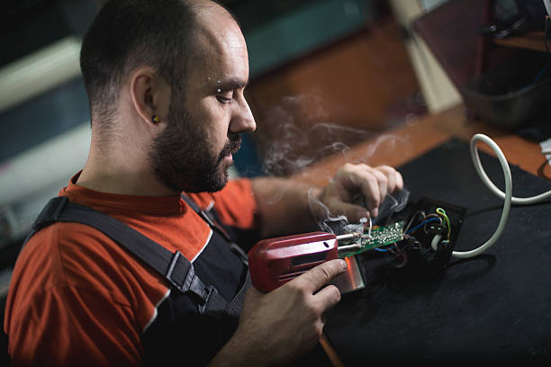istock Repairman working in workshop and soldering electric board 577336196