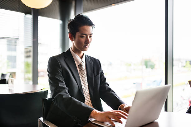 homme d’affaires sur l’ordinateur dans la salle de réunion du bureau - laptop japanese ethnicity businessman desk photos et images de collection