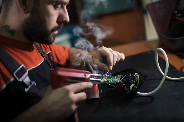 istock Repairman working in workshop and soldering electric board 577336658