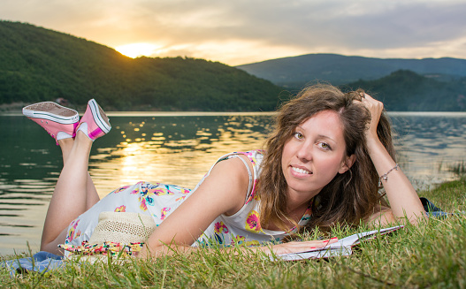 Young woman reading a book by the lake. Solo relaxation