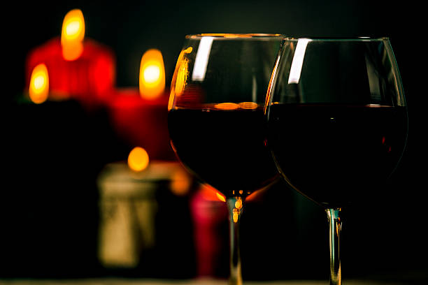 Two red wine, glasses and candles. Christmas or holiday celebration.