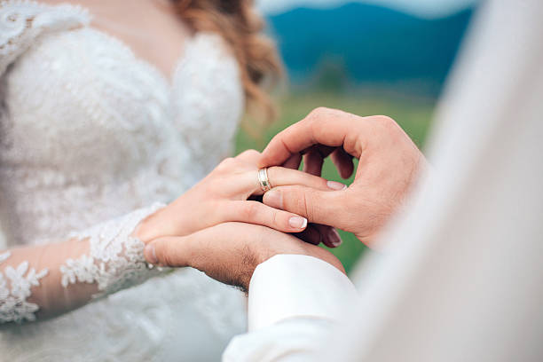istock mans hand putting a wedding ring on the brides 577341096