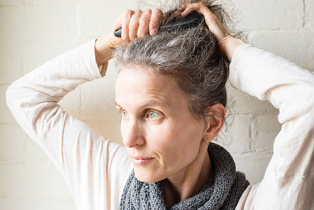 istock Middle aged woman brushing grey hair 577343406