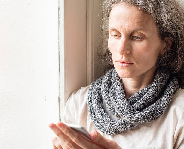 istock Thoughtful middle aged woman with smart phone 577343556