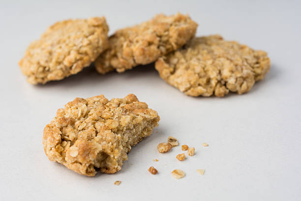 istock Four oatmeal cookies with bite and crumbs on white counter 577345438