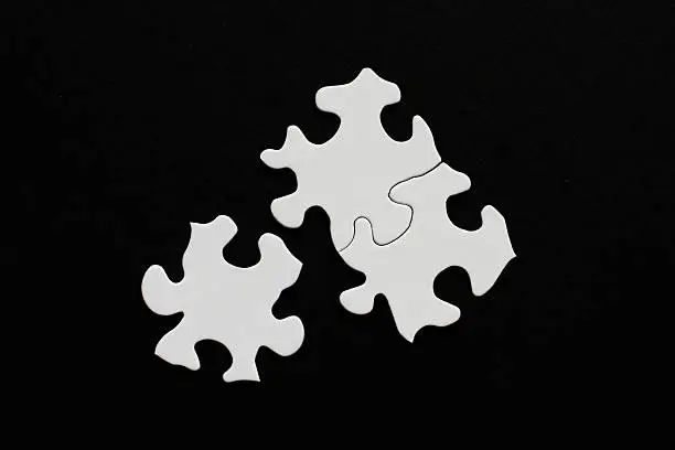 Photo of Three blank puzzle pieces on black background one unlinked