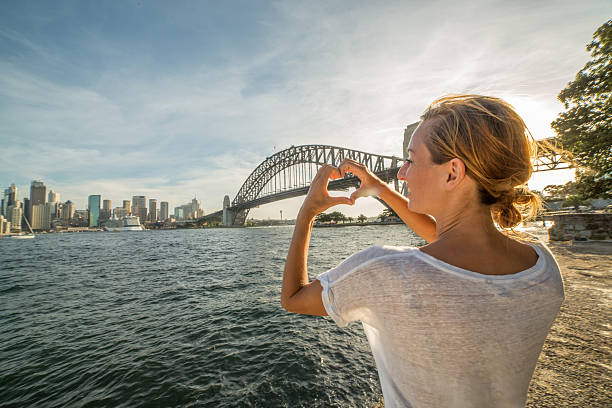 istock Beautiful girl makes heart shape finger frame on Sydney skyline 577346418