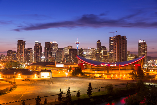 Skyline of Calgary Alberta Canada with the illuminated Scotiabank Saddledome arena at night.