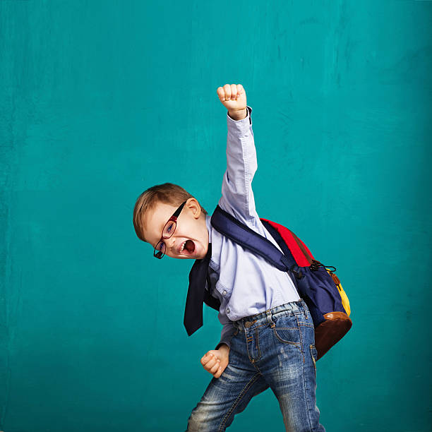 smiling little boy with big backpack jumping and having fun Cheerful smiling little boy with big backpack jumping and having fun against blue wall. Looking at camera. School concept. Back to School rucksack stock pictures, royalty-free photos & images