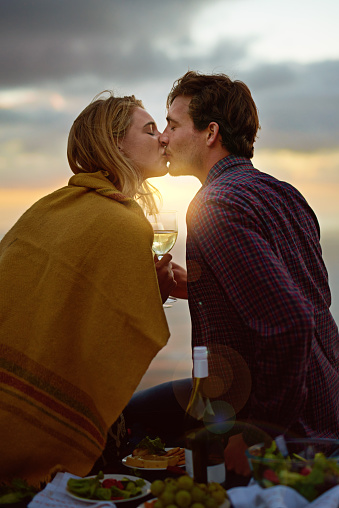 Shot of a young couple kissing on a romantic picnic at sunset