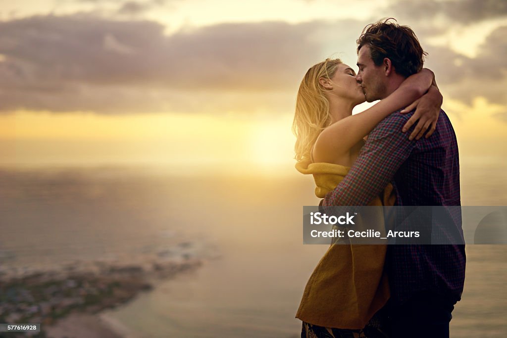 The stuff romance novels are made of Shot of a romantic young couple sharing a passionate kiss at sunset Kissing Stock Photo