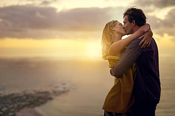 The stuff romance novels are made of Shot of a romantic young couple sharing a passionate kiss at sunset kissing stock pictures, royalty-free photos & images