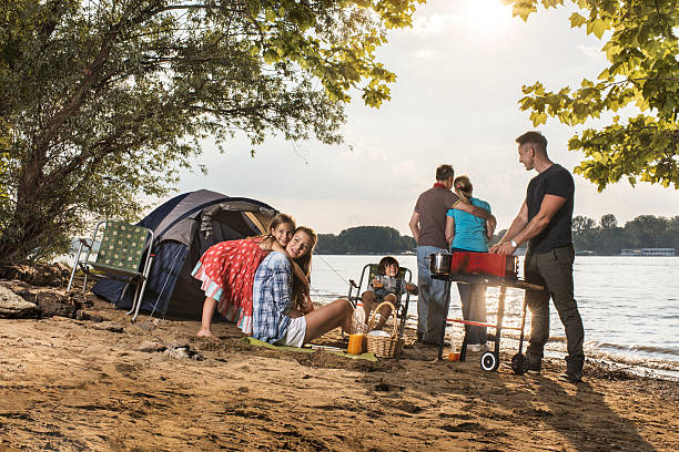 Happy extended family spending a day on camping. Smiling multi-generation family relaxing during a camping day by the river. family bbq beach stock pictures, royalty-free photos & images