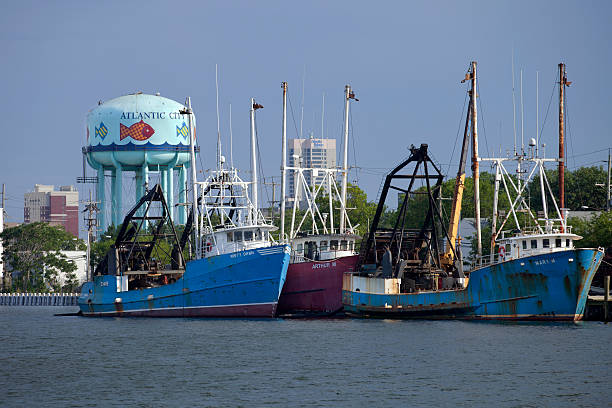 Atlantic City, New Jersey, USA - July 16, 2016: Commercial fishing boats docked in the marina district in the north end of Atlantic City, New Jersey with casino and watertower in the background.