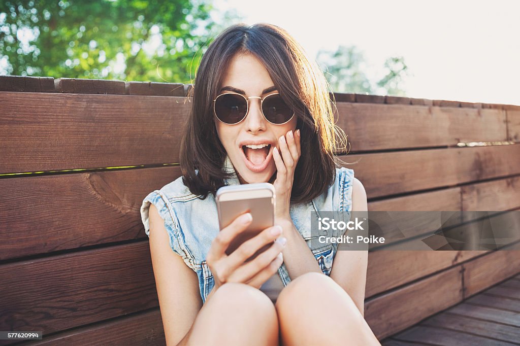 Surprised girl using smart phone Happy young woman using smart phone Smart Phone Stock Photo