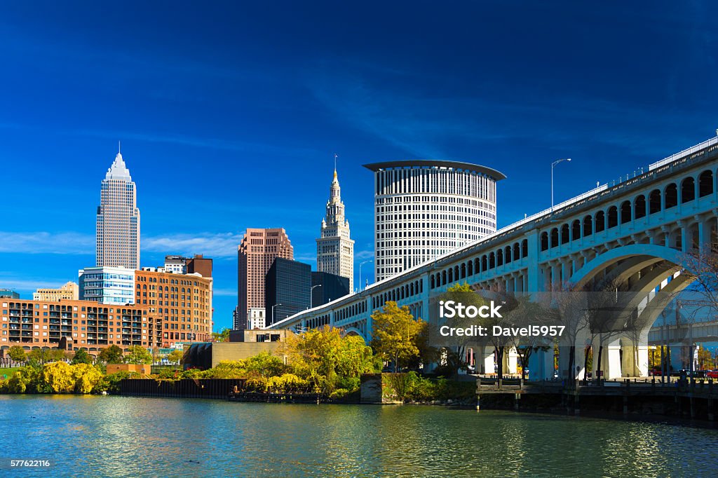 Downtown Cleveland with River, Bridge, Trees, and Deep Blue Sky Downtown Cleveland skyline (featuring Key Tower) with the Cuyahoga River, Detroit-Superior Bridge, Autumn colored trees, and a deep blue sky with wispy clouds.  Wide Angle. Cleveland - Ohio Stock Photo