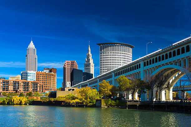 Downtown Cleveland with River, Bridge, Trees, and Deep Blue Sky Downtown Cleveland skyline (featuring Key Tower) with the Cuyahoga River, Detroit-Superior Bridge, Autumn colored trees, and a deep blue sky with wispy clouds.  Wide Angle. river cuyahoga stock pictures, royalty-free photos & images