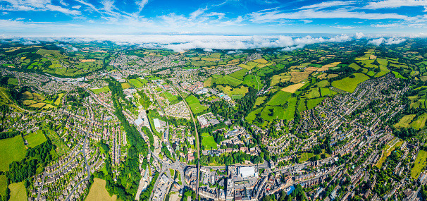 Aerial view over homes, streets and suburban community at the edge of picturesque country town surrounded by green pasture and farmland, Stroud, UK. ProPhoto RGB profile for maximum color fidelity and gamut.
