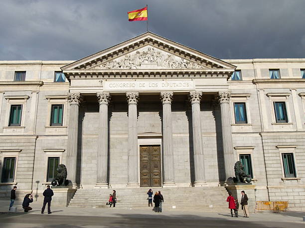 Madrid, Spain-January 2, 2011: Deputies Spanish Congress in Madrid, the Spanish Parliament lower house. Building facade and lion statues in the foreground. People walking on the sidewalk this winter sunny day.