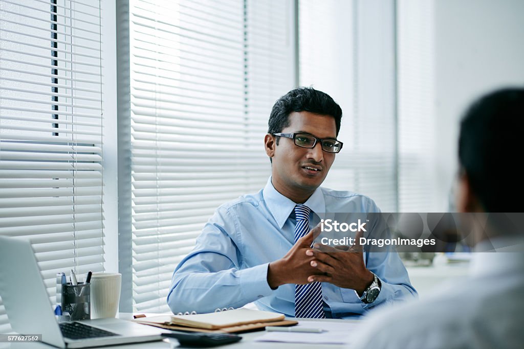 Consulting coworker Handsome young businessman talking to his colleague Culture of India Stock Photo