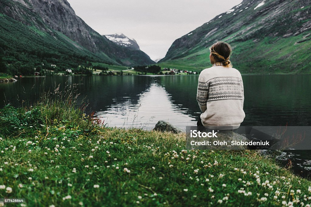 Woman near the lake Young caucasian woman sitting near the mountain lake in Norway Nature Stock Photo