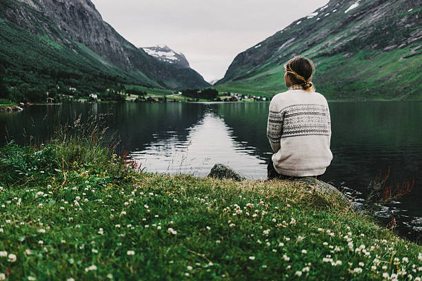 Woman near the lake Young caucasian woman sitting near the mountain lake in Norway fjord photos stock pictures, royalty-free photos & images