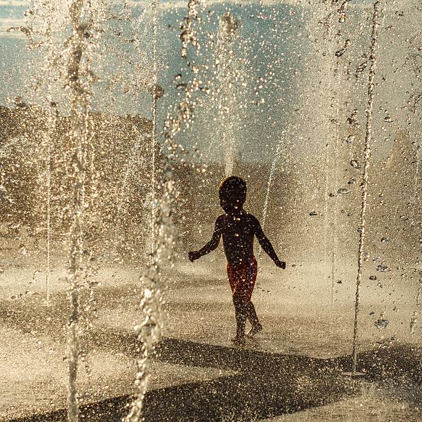 istock baby runs in the fountain sunlight 577630622
