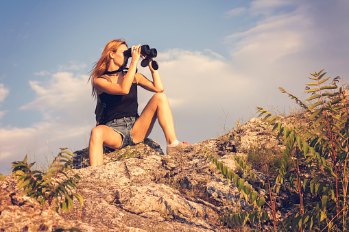 Woman using binoculars to see from the top of hill