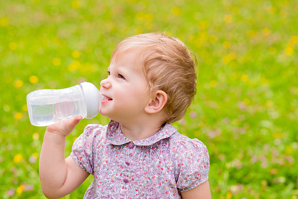 Thirsty Cute baby drinking water from bottle outside