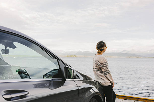 Woman near the car Young caucasian woman standing near the car on the background of the fjord in Norway lake scandinavia stock pictures, royalty-free photos & images