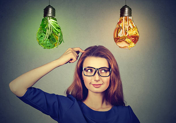 istock Woman thinking deciding on diet at junk food light bulb 577641812
