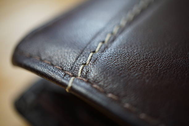 istock Macro detail of white thread stitching black leather wallet 577644200