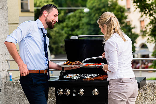 Office colleagues grilling sausages at bbq after work