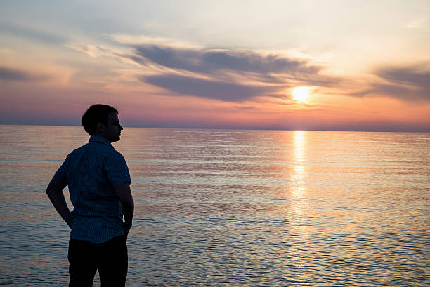 istock Young man standing at the beach in front of amazing 577650740