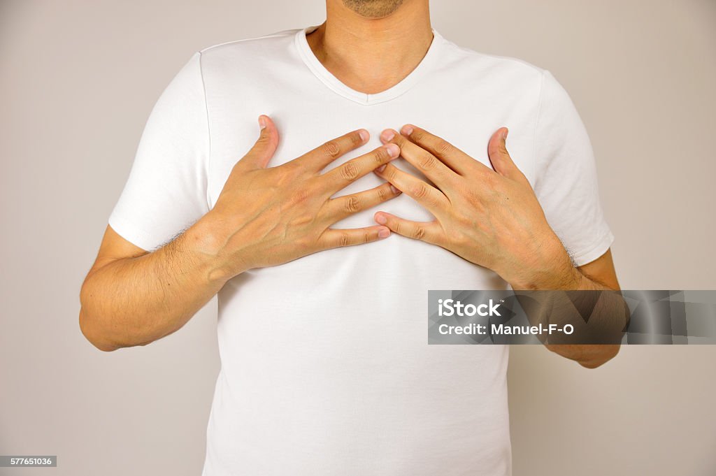 man with respiration problems man with both hands on breast because of hard breathing and angina pectoris on grey background Breast Stock Photo