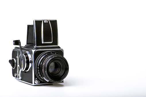 An old medium format camera with bellows lens from the 1940-50s on white background close up.