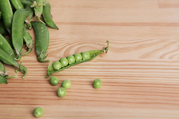 green peas in pods freshly picked on wooden background texture