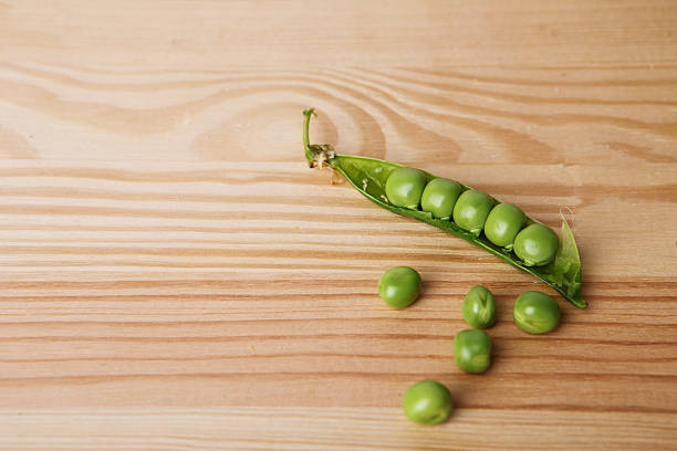 green peas in pods freshly picked on wooden background texture