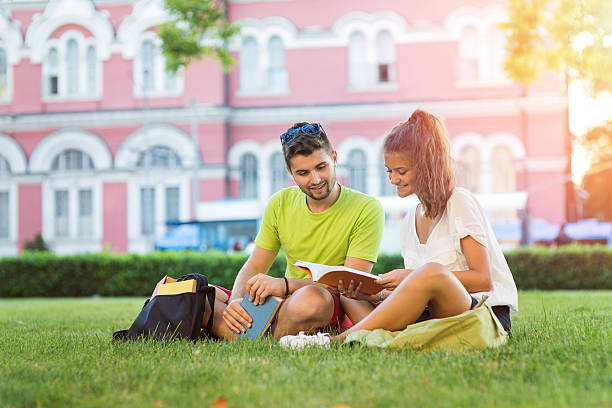 estudiantes que leen en el campus - school year fotografías e imágenes de stock