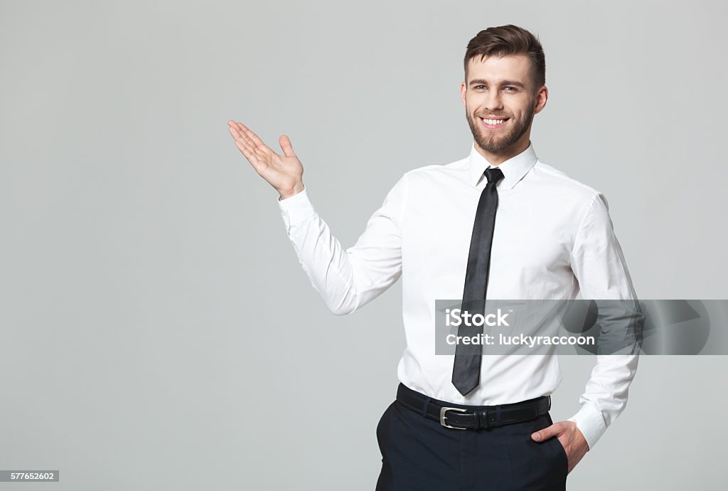 Handsome young businessman holding his arm up presenting copyspace. Your logo or product goes here! Studio shot of handsome young businessman holding his arm up presenting copyspace. Pointing Stock Photo