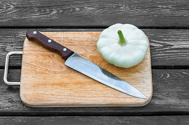 Squash on a cutting board wooden background with steel knif Squash on a cutting board on wooden background with a steel knife knif stock pictures, royalty-free photos & images